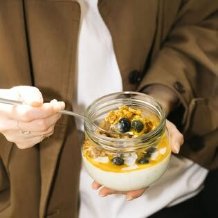 Parfait cu iaurt și fructe într-un borcan, ținut în mână